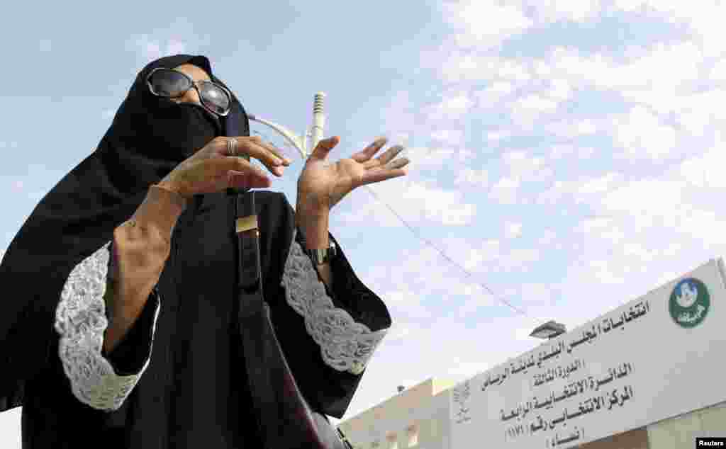 A woman gestures as she leaves a polling station after casting her vote.