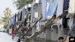 Residents staying at a concrete block, part of construction for an elevated train system, pass the time, in a flooded area on the outskirts of Bangkok November 11, 2011.