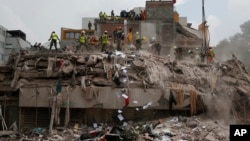 Workers shovel papers and debris off the top of the rubble of a building that collapsed in last week's 7.1 magnitude earthquake, at the corner of Gabriel Mancera and Escocia streets in the Del Valle neighborhood of Mexico City, Monday, Sept. 25, 2017. 