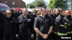 Members of the emergency services attend a minute's silence for the victims of the Grenfell Tower fire near the site of the blaze in North Kensington, London, June 19, 2017.