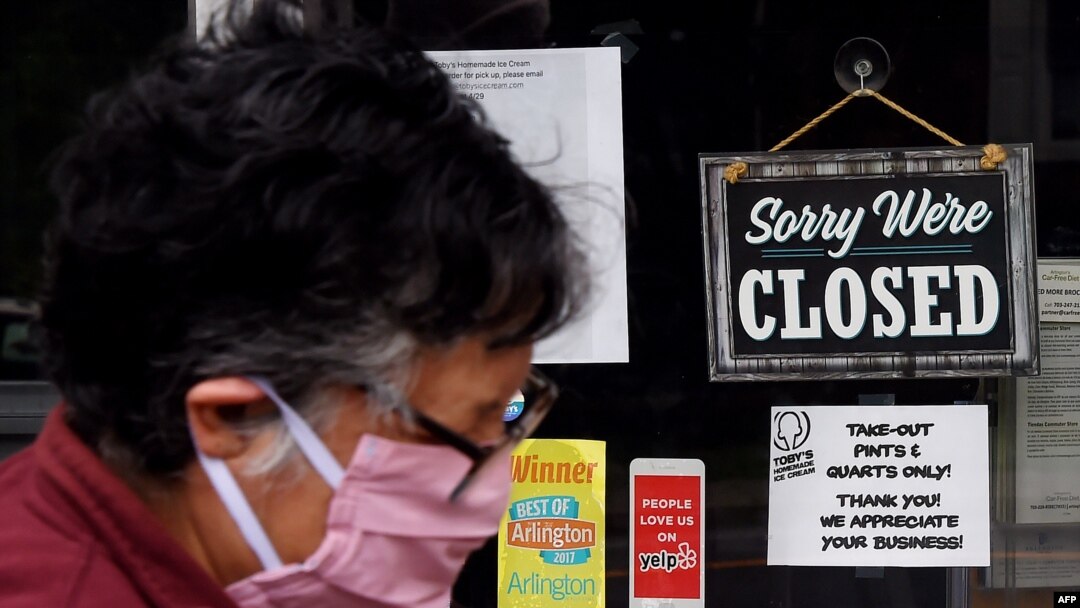 Seorang perempuan mengenakan masker berjalan melewati tanda di jendela toko makanan yang tutup selama pandemi Covid-19 di Arlington, Virgina, 4 Mei 2020. (Foto: dok).