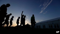 At sunrise, migrants are escorted to a tent that serves a dining hall for the U.S. government's newest holding center for migrant children in Carrizo Springs, Texas, July 9, 2019.