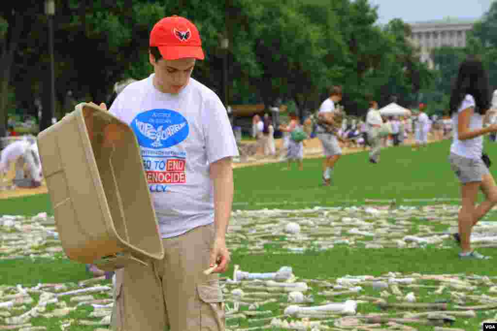 A volunteer lays artificial bones at the &quot;One Million Bones&quot; installation on the National Mall, Washington, D.C, June 8, 2013. (Jill Craig/VOA)