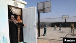 FILE - Syrian refugees peep out from a door in Al Zaatari refugee camp near Mafraq, Jordan near the border with Syria, March 28, 2017. 