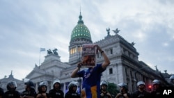 Un manifestante frente al Congreso sostiene un periódico que dice "Milei defraudador", después de una protesta en Buenos Aires, Argentina, el miércoles 26 de febrero de 2025. (Foto AP/Natacha Pisarenko).