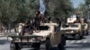 FILE - Armed Taliban fighters parade atop humvee vehicles as they celebrate the first anniversary of the withdrawal of US-led troops from Afghanistan, near the former US embassy in Kabul on Aug. 31, 2022. 