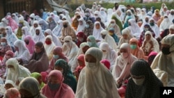 Muslims wear face masks as a precaution against the coronavirus during Eid al-Fitr prayer marking the end of the holy fasting month of Ramadan on a street in in Bekasi, West Java, Indonesia, May 13, 2021.