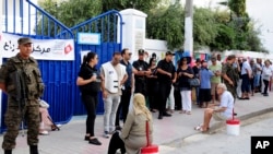 Security forces stand guard as voters queue outside a polling station during the first round of the presidential election, in La Marsa, outside Tunis, Tunisia, Sept. 15, 2019.