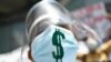 Una trabajadora de la salud usa doble protección. Su mascarilla está marcada con un signo de dólar en apoyo de la dolarización, participa en una protesta por el Primero de Mayo, o Día Internacional de los Trabajadores, en Caracas.