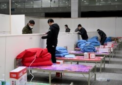 FILE - Workers set up infrastructure at the Wuhan International Conference and Exhibition Center to convert it into a makeshift hospital to receive patients infected with the coronavirus, in Wuhan, Hubei province, China, Feb. 4, 2020.