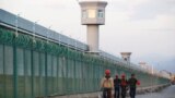 FILE PHOTO: Workers walk by the perimeter fence of what is officially known as a vocational skills education centre in Dabancheng in Xinjiang Uighur Autonomous Region, China September 4, 2018. REUTERS/Thomas Peter/File Photo