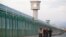 FILE PHOTO: Workers walk by the perimeter fence of what is officially known as a vocational skills education centre in Dabancheng in Xinjiang Uighur Autonomous Region, China September 4, 2018. REUTERS/Thomas Peter/File Photo