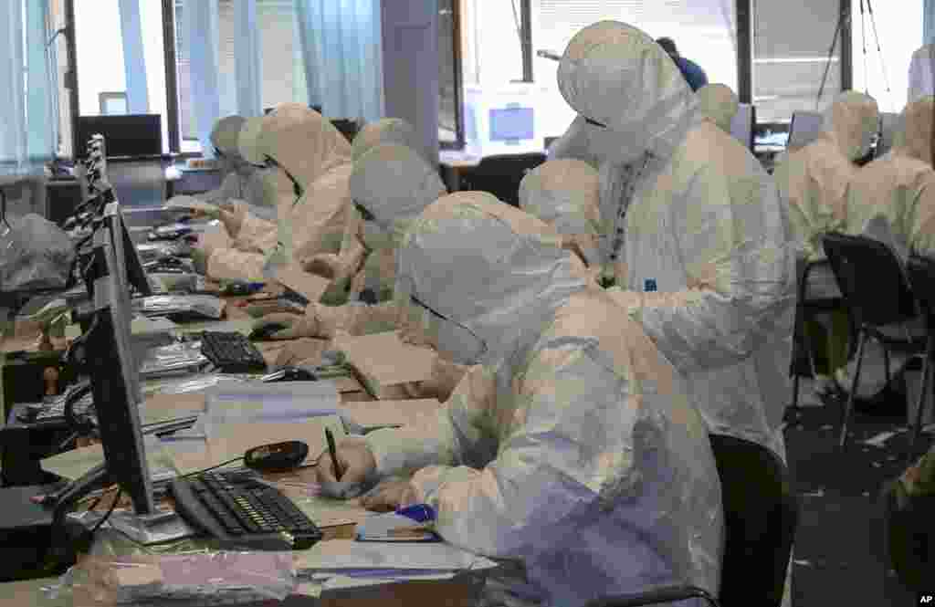 Central Election Commission officials wearing disposable overalls and masks count votes from Serbia in the Kosovo capital Pristina. Vote counting has been suspended as several officials reported health problems after opening ballot boxes from Serbia.