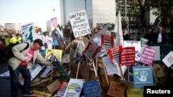 Seorang lelaki meletakkan plakat di luar Gedung Parlemen, setelah parlemen membahas Brexit, duduk pada hari Sabtu untuk pertama kalinya sejak Perang Falklands 1982, di London, Inggris, 19 Oktober 2019. (Foto: Reuters / Henry Nicholls)