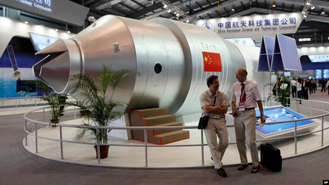 FILE - Visitors sit besides a model of Chinese made Tiangong 1 space station at the 8th China International Aviation and Aerospace Exhibition, known as Airshow China 2010, in Zhuhai city, south China, Guangdong province, Nov. 16, 2010.