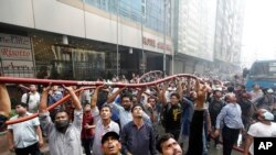 Locals help firefighters work to douse a fire in a multistoried office building in Dhaka, Bangladesh, March 28, 2019. 