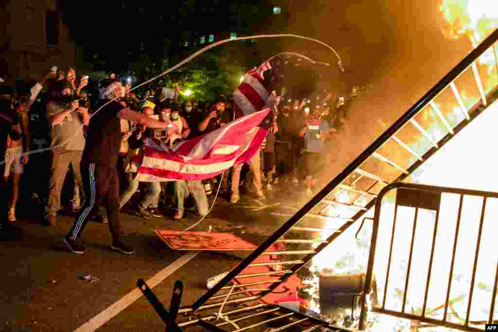 Protesters throw a US flag into a fire during a demonstration outside the White House over the death of George Floyd at the hands of Minneapolis Police in Washington, DC, on May 31, 2020.