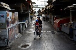A woman rides a bicycle with her child in a closed market after Israel imposed a second nationwide coronavirus disease (COVID-19) lockdown amid a rise in infections in Tel Aviv, Israel, Sept. 25, 2020.