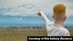 Nodumo Ncomanzi points towards Mt Kilimanjaro, Moshi, Kenya, March, 2018. 