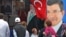People walk past a poster of Turkey's Prime Minister and leader of the Justice and Development Party (AKP) Ahmet Davutoglu (R) in Istanbul, Turkey, June 5, 2015. 