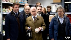 French Interior Minister Bernard Cazeneuve, center, buys items at the Hyper Cacher kosher supermarket in Paris that became the site of a bloody hostage drama in January. The supermarket has been fully renovated, March 15, 2015.