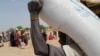 A worker of World Food Programme (WFP) carries a bag of relief grains to be distributed to Sudanese refugees who have fled the violence in their country, near the border between Sudan and Chad, in Koufroun, Chad April 28, 2023.