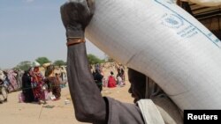 A worker of World Food Programme (WFP) carries a bag of relief grains to be distributed to Sudanese refugees who have fled the violence in their country, near the border between Sudan and Chad, in Koufroun, Chad April 28, 2023.