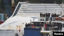 Relatives of victims stand on a ferry in front of the capsized cruise liner Costa Concordia outside Giglio harbor, Italy, January 13, 2013. 