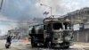 FILE - A man on a scooter rides past a damaged water tanker that was set afire during a protest by tribal groups in Churachandpur, in the northeastern Indian state of Manipur, May 4, 2023.