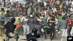 Iraqi anti-government protesters throw stones and trash at riot police during a demonstration in Baghdad, Iraq, Friday, Feb. 25, 2011. Thousands marched on government buildings and clashed with security forces in cities across Iraq on Friday, in the large