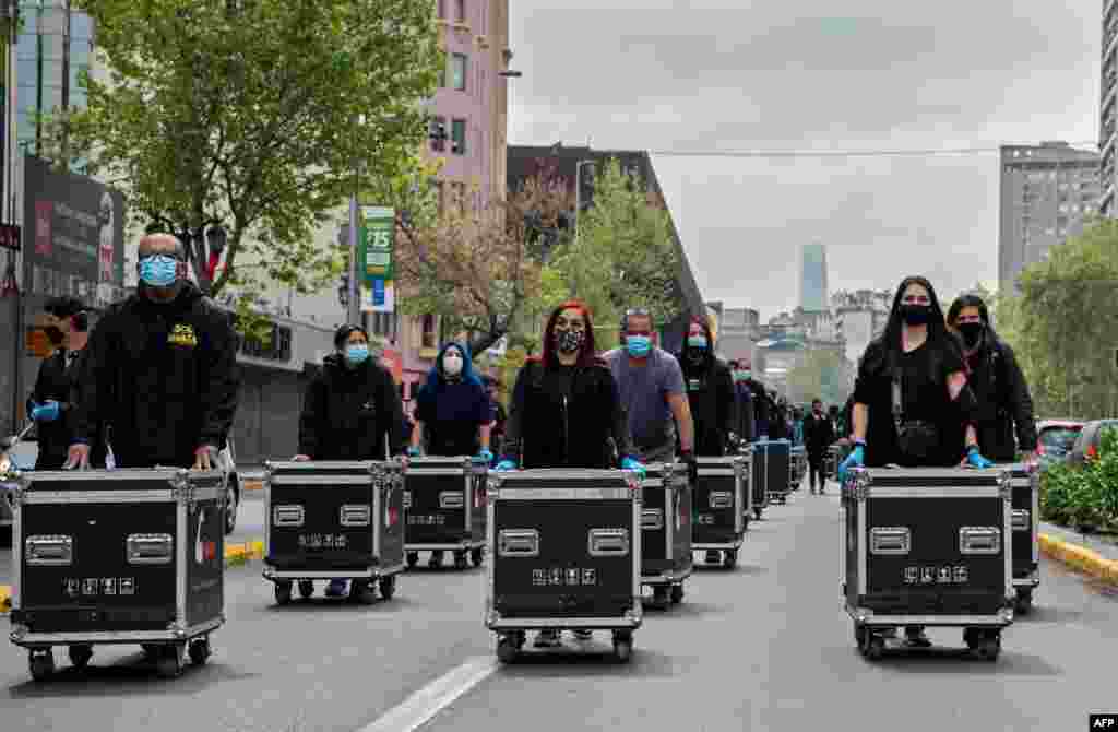 Members of the Arts and Shows Association Union push boxes with lights and wires during a protest demanding support from the government of Chilean President Sebastian Pinera during the coronavirus pandemic, in Santiago, Sept. 29, 2020.