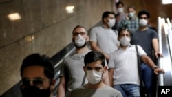 FILE - People wear protective face masks to help prevent the spread of the coronavirus as they ride an escalator at a metro station, in Tehran, Iran, July 8, 2020. 