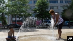 Karen Frazier of Capitol Heights, Md., and her son Amari Rogers 11, play in a fountain in Washington, July 20, 2019. The National Weather Service said "a dangerous heat wave" was expected to break record highs in some places.