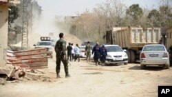 Photo released by the Syrian official news agency SANA on March, 22, 2108 shows Syrian government forces overseeing the evacuation by buses of rebel fighters and their families, at a checkpoint in eastern Ghouta, Syria. 
