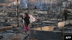 Syrian refugees salvage belongings from the wreckage of their shelters at a camp set on fire overnight in the northern Lebanese town of Bhanine on December 27, 2020, following a fight between members of the camp and a local Lebanese family. 