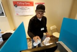 John Davis, a polling judge volunteer, sanitizes an electronic voting machine screen amid concerns about the COVID-19 coronavirus at a polling place in the Bronzeville neighborhood of Chicago, March 17, 2020.