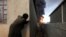 A woman looks at fire and smoke from oil wells set ablaze by Islamic State militants before the fled the oil-producing region of Qayyara, Iraq, Nov. 4, 2016. 