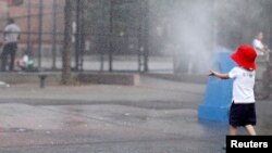 A young boy cools off in the water from a playground sprinkler in the Brooklyn borough of New York, July 15, 2013. 