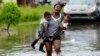 Terrian Jones menggendong dua anak, Drew dan Chance Furlough, untuk dibawa ke orangtuanya, saat banjir melanda Jalan Belfast di kota New Orleans, Louisiana.