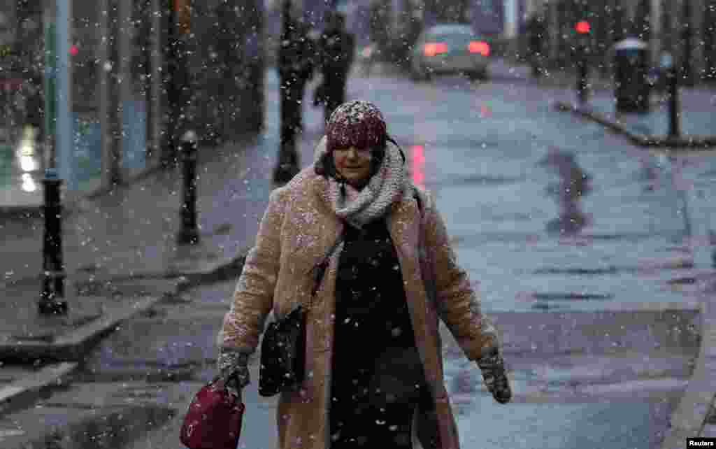 A pedestrian walks along a street during the first snow fall of the season in Rickmansworth, Britain. REUTERS/Suzanne Plunkett