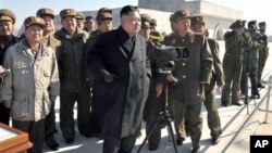 Pemimpin Korut, Kim Jong Un disertai para pejabat militer meninjau latihan artileri militer Korea Utara, Kamis (14/3). 