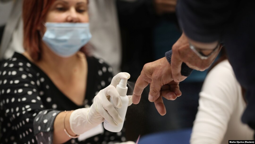 Članica biračkog odbora, sa zaštitnom maskom na licu kao zaštitom od koronavirusa, obeležava birača koji je glasao u Beogradu, tokom epidemije Kovida 19, u Beogradu, 21. juna 2020. (REUTERS/Marko Đurica)