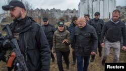 El fiscal de la Corte Penal Internacional, Karim Kahn (segundo en primer plano a la derecha), conversa con la fiscal general de Ucrania durante su visita a un cementerio en Bucha, Ucrania, en esta foto de archivo de marzo pasado. 