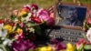 FILE - A rosary covers a photograph of President John F. Kennedy at a marker along Elm Street, where the former president was assassinated, as flowers adorn the memorial on the 60th anniversary of his assassination, Nov. 22, 2023, in Dallas.