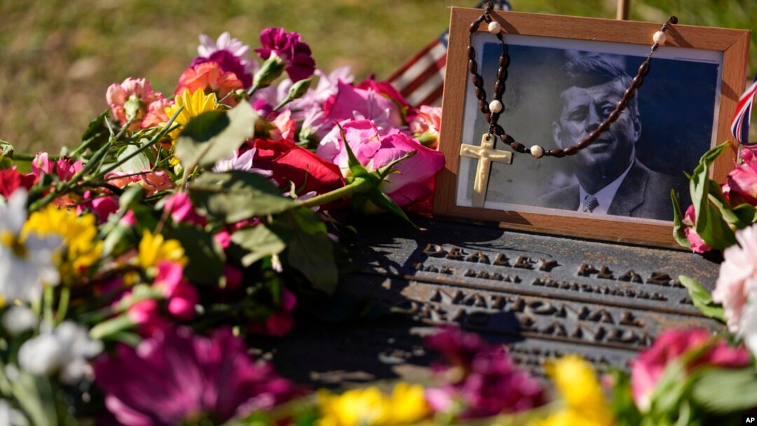FILE - A rosary covers a photograph of President John F. Kennedy at a marker along Elm Street, where the former president was assassinated, as flowers adorn the memorial on the 60th anniversary of his assassination, Nov. 22, 2023, in Dallas, Texas.