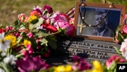 FILE - A rosary covers a photograph of President John F. Kennedy at a marker along Elm Street, where the former president was assassinated, as flowers adorn the memorial on the 60th anniversary of his assassination, Nov. 22, 2023, in Dallas, Texas.