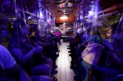 FILE - Plastic sheets on a traditional Jeepney bus separate passengers as part of health measures to help prevent the spread of the new coronavirus in metropolitan Manila, Philippines, July 3, 2020.