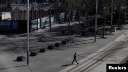 A person crosses a light rail track at Circular Quay in Sydney, Australia, as the state of New South Wales continues to report relatively low numbers for new daily cases of the COVID-19, Sept. 7, 2020.