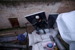 A Syrian youth loads solar panels among other belongings onto a truck before leaving the town of Binnish in the northwestern province of Idlib, Feb. 4, 2020, amid an ongoing offensive by pro-regime forces.