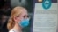 A woman wears a mask against the coronavirus disease (COVID-19), following the CDC recommendation that fully vaccinated Americans wear masks as the highly transmissible Delta variant has led to a surge in infections, as she enters the Disney Store in Time